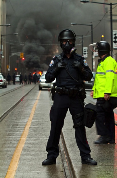 Police officer blocking the crowd with police car on fire at the G20 Summit in Toronto -  Photography 401 - Photographed by Peter Gatt School of Photography